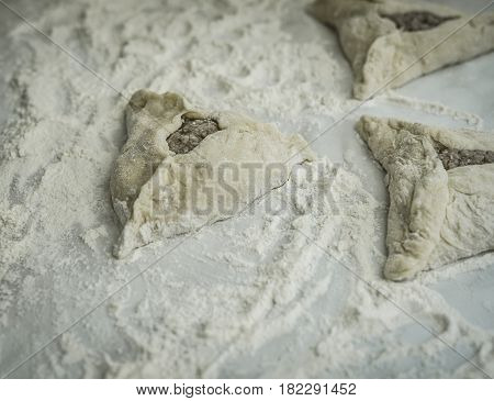 Baking peremech concept. Flour, dough and meat cooking ingredients. Hands top view of cooking belyash cuisines. wrepped ground meat with hole in flour ready for cooking.
