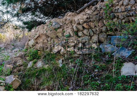 Mud brick wall with black tile roof fallen into state of disrepair in wooded area South Korea