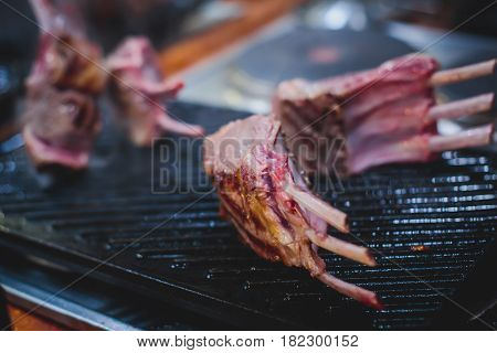 Different stages of cooking the steak on a kitchen, barbeque, roasted lamb ribs, big dish plate with roasted full pork head, served in restaurant with vegetables, lamb, ham and chicken.