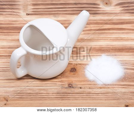 Ceramic neti pot and saline on wooden vintage background