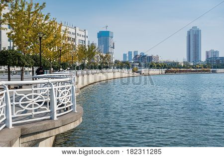 Tianjin, China - Nov 1, 2016: Shoreline along the Haihe River as viewed from Tianjin Railway Station. Image features a modern public walkway with railings.