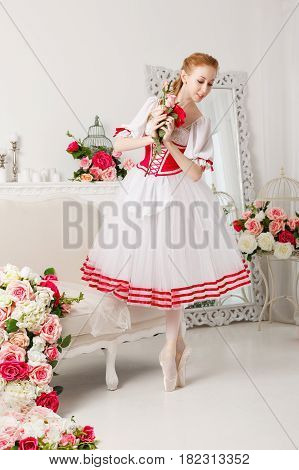 Pretty ballerina in stage costume holding a bouquet of spring flowers. Retro dress. She dreams. She's a slender girl.