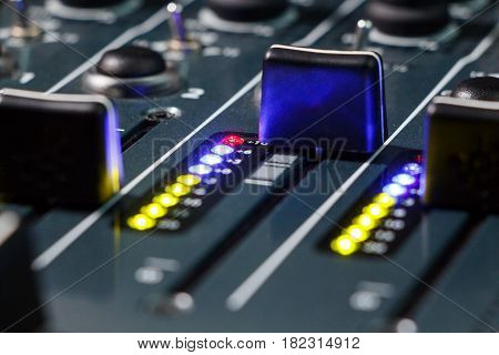 Close up shot of a DJ mixer volume faders with volume levels in the red