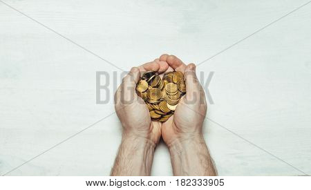 Male hands with a handful of coins in the palms on a light white background. Flat style