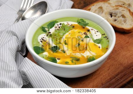 Pea puree soup with poached egg sour cream mint leaves seasoned with spices.