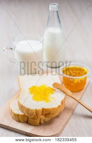 Breakfast with milk sliced bread and jam on the wooden table
