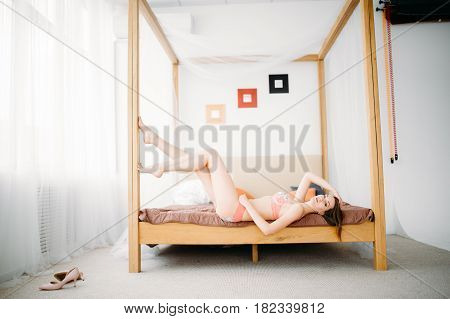 Beautiful Naked Girl Sitting On The Bed And Looking Out The Window At The Morning Sun.