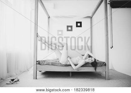 Beautiful Naked Girl Sitting On The Bed And Looking Out The Window At The Morning Sun.