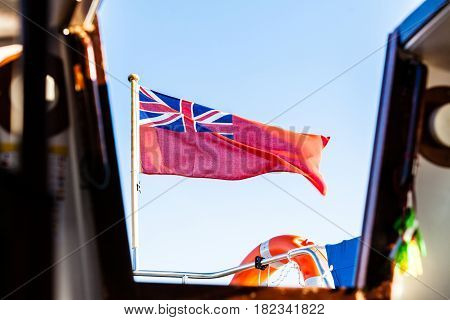 The uk red ensign the british maritime flag flown from yacht sail boat blue sky and baltic sea. Summer and travel voyage