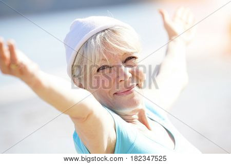 Senior blond woman doing yoga exercices on the beach