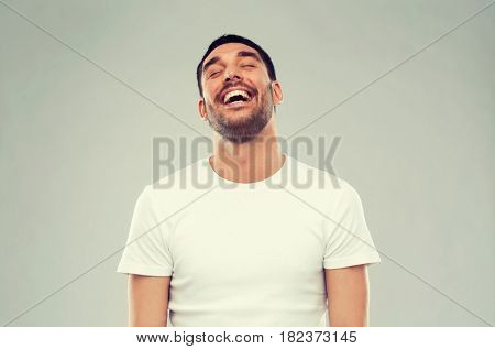 emotion and people concept - laughing man over gray background
