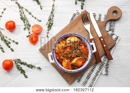 Bowl with delicious chicken cacciatore on wooden board
