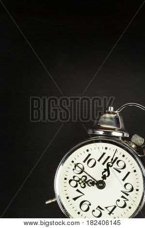 Retro metal alarm clock on a black wooden background. Open your eyes. Reveille to wake up. Place for text