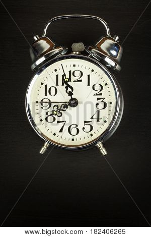Retro metal alarm clock on a black wooden background. Open your eyes. Reveille to wake up. Place for text