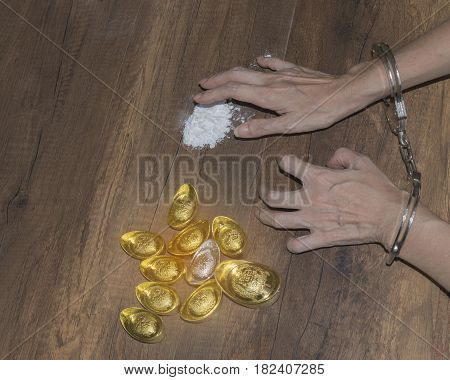 The chrome metal handcuffed bondage on man hand during holding gold bar represent the crime fraud and punishment equipment concept related idea. Addictive substance no freedom Translation in English meaning lucky and richly