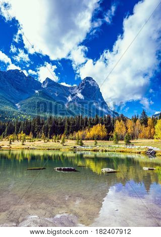Shallow lakes surrounded by mountains and forests. Shining day in Canmore, Canadian Rockies. Concept of hiking