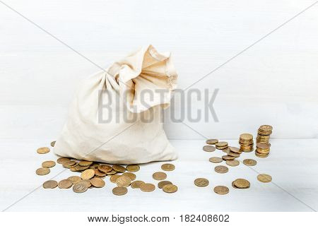 Money bag and gold coins on white wooden background