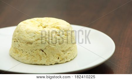 French baked cheese souffle on white plate close-up on the wooden table. horizontal
