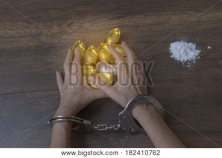 The chrome metal handcuffed bondage on man hand during holding gold bar represent the crime fraud and punishment equipment concept related idea. Addictive substance no freedom Translation in English meaning lucky and richly