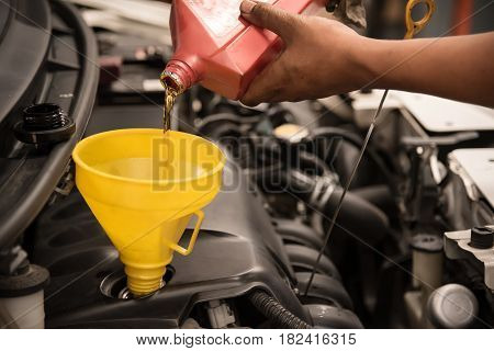 Close up man hands. Mechanic pouring new engine oil to car engine.