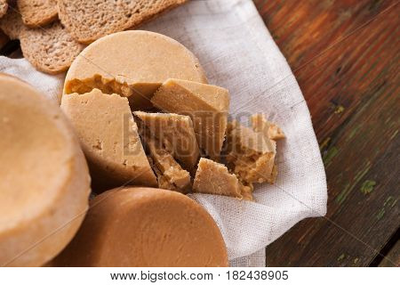 Norwegian homemade brown cheese brunost with crackers or crispbread on wooden desk, close-up, selective focus