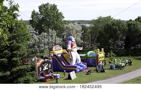 Laval, Quebec - June 14, 2015 - Landscape view of a large football themed blow up play equipment with a group of people waiting to jump inside at the 