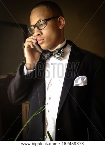 Young African American man standing in a tuxedo while on the phone looking good