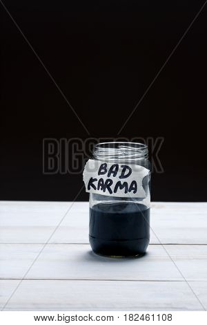 Bad Karma - an inscription on the label of a glass jar with a liquid of black color on a black and white background