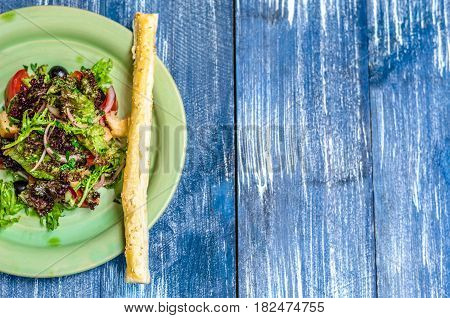 Salad Of Tomatoes, Olives, Onions And Herbs, With A Bread Stick With Sesame Seeds