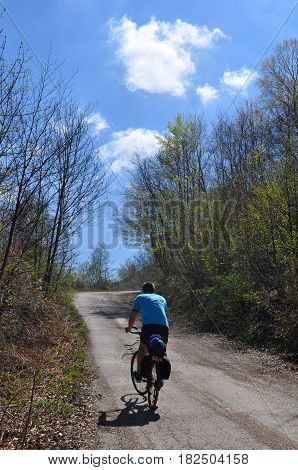 Men riding bicycle up mountain road in beautiful spring day. Bicycle tourism concept