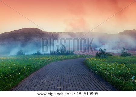 Foggy summer sunrise in Great Geysir valley on the slopes of Laugarfjall hill. Colorful morning scene in Southwestern Iceland Europe. Artistic style post processed photo.