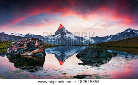 Colorful summer sunrise on the Stellisee lake. Reflection of Matterhorn (Monte Cervino Mont Cervin) peak in the watter surface. Beautiful outdoor scene in Swiss Alps Zermatt location Valais canton Switzerland Europe.