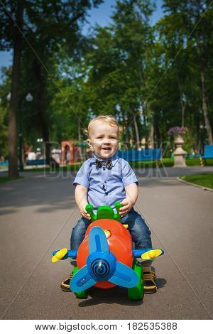 Little kid boy driving color toy car and having fun outdoors. Child enjoying warm summer day in nature landscape