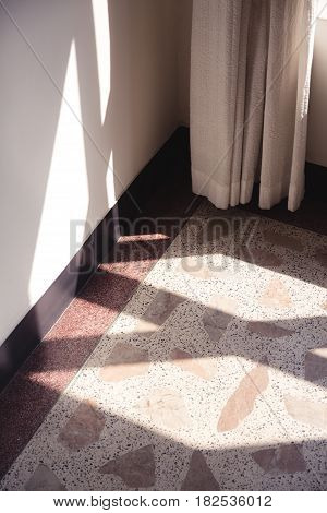 Early morning light streaming through a window and onto a floor made of terrazzo tiles and wall.