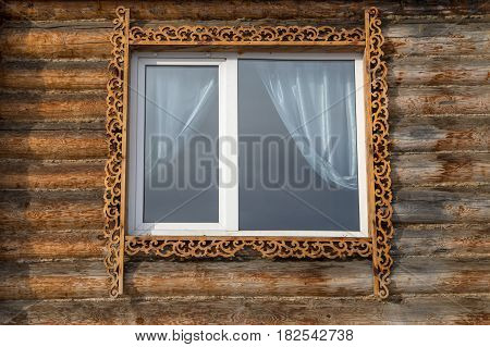 A window with a carving in a wooden house.