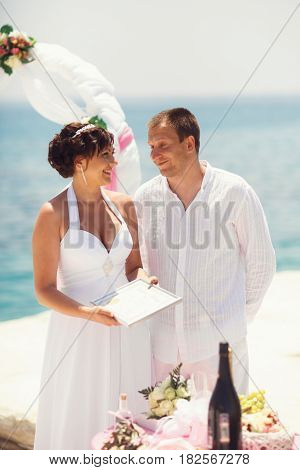 Man And Woman Look At Each Other With Standing Behind A Wedding Altar By The Sea