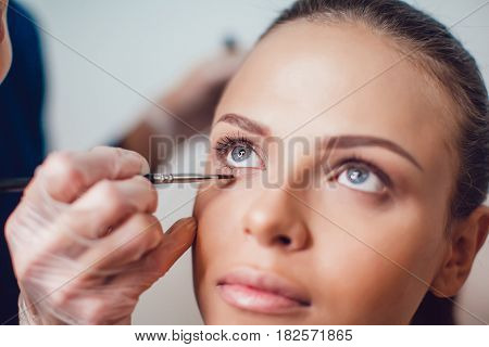 Professional make-up artist makes eye makeup of model. Beauty and fashion concept. Close up.