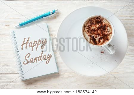 Sketchpad and cup of hot cocoa. Inscription in a notebook: Happy sunday