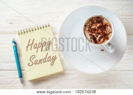 Sketchpad and cup of hot cocoa. Inscription in a notebook: Happy sunday