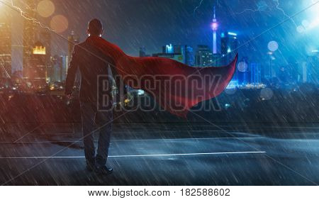 Businessman in a suit and cape hero facing a stormvictory concept. cityscape background night scene .