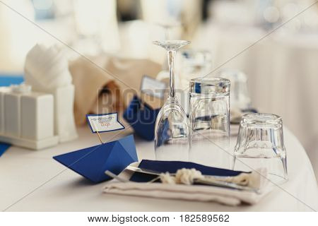 Little blue paper ships lie behind the glassware on a dinner table