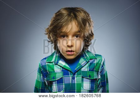 Closeup Portrait of handsome boy with astonished expression while standing against grey background.