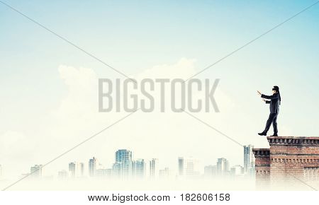Businessman with blindfolder on eyes walking on building top