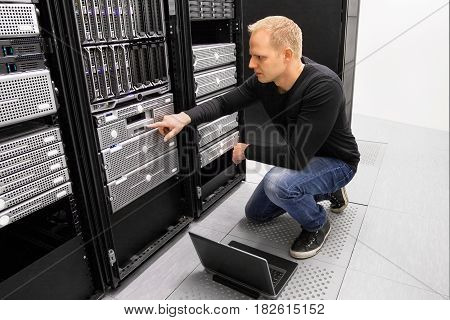 It engineer or consultant working with laptop and maintaining servers in data center.
