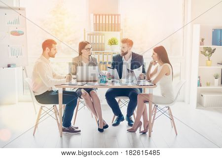 Group Of Successful Young Businesspartners Are Having Serious Conversation While Working Around Tabl