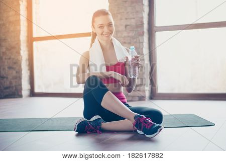 Attractive Young Sportwoman Finished Her Work Out And Now Drinking Water And Smiling. She Is Sitting