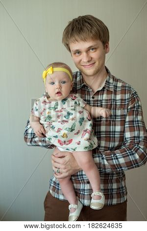 Beautiful happy smiling daddy of European appearance holds on the hands of a little baby girl