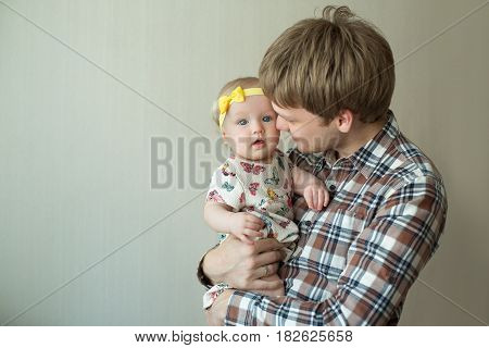 Beautiful happy smiling daddy of European appearance holds on the hands of a little baby girl