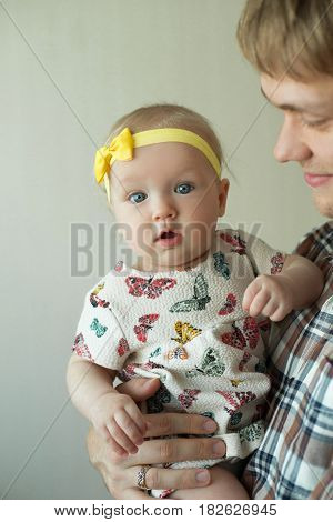 Beautiful happy smiling daddy of European appearance holds on the hands of a little baby girl