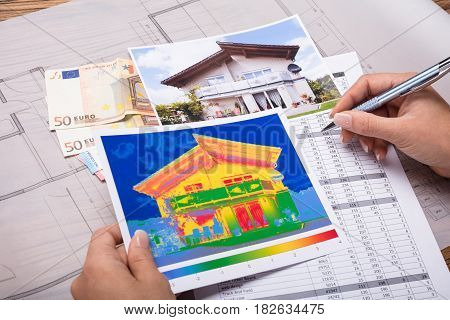 Close-up Of A Woman Calculating Heat Temperature With Euro Notes On Desk